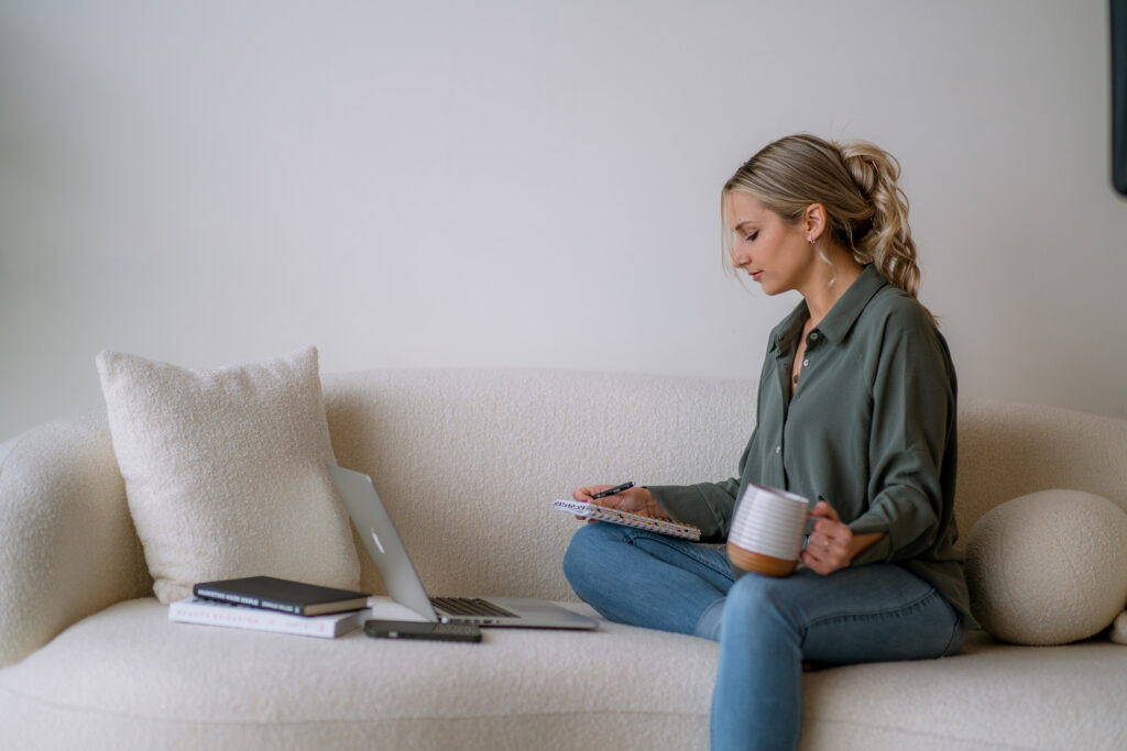 Competitive analysis for small business: person taking notes while reviewing competitor brands on a laptop.