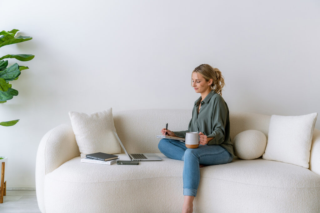 Service provider drafting website copy for services on a laptop while reviewing notes for clearer messaging
