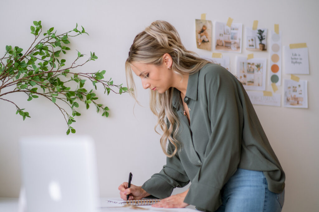 Brand identity designer sketching ideas at a desk with a mood board and laptop nearby